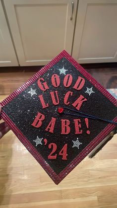 a graduation cap with the words good luck babe in red and black glitter on it