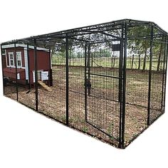 an outdoor chicken coop with a red house in the background