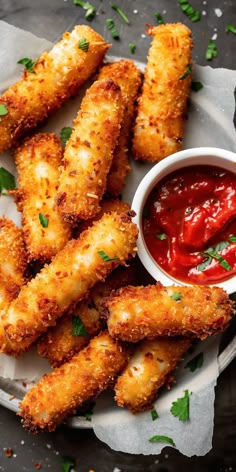 some fried food is on a plate with ketchup and dipping sauce in it