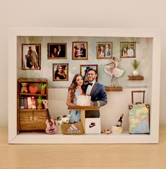 a man and woman standing in front of a table with pictures on the wall behind them