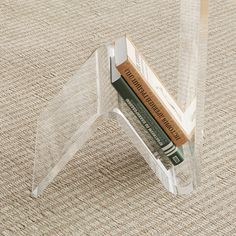 a clear acrylic book holder with books in it on a carpeted surface