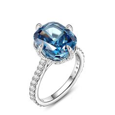 This is a stunning blue stone ring that exudes elegance and sophistication. The centre of the ring is set with a large, captivating blue stone that commands attention with its deep, enchanting hue. The sparkling centre stone is also set with a hidden halo of smaller round stones, and the glittering stone-set band adds to the brilliance of this chic ring. The smooth and delicate design ensures a comfortable fit while showcasing the beauty of the central blue stone.Carat Weight: 6.29 ctStone Size: 10*12 mmStone Type: Jeulia® StoneNumber of Stones: 1 Stone Color: Aquamarine BlueStone Shape: Fat OblongCarat Weight: 1.381 ctStone Size: 1,1.2,1.7,0.8 mmStone Type: Jeulia® StoneNumber of Stones: 68 Stone Color: Diamond WhiteStone Shape: RoundWeight: 2.9 gWidth: 1.9 mmHeight: 10 mmThickness: 1.5 m Blue Open Ring Crystal Fine Jewelry, Blue Diamond Ring With Gemstone Accents, Fine Jewelry Blue Open Diamond Ring, Blue Crystal Gemstone Ring, Dazzling Blue Diamond Promise Ring, Blue Diamond Ring With Gemstone Accents For Promise, Elegant Sapphire Ring With Diamond Setting, Elegant Blue Sapphire Halo Ring, Blue Cushion Cut Cubic Zirconia Rings