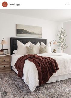 a bedroom with a large bed and rugs on the floor in front of it