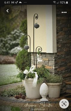 two white pots with plants in them sitting on the ground next to a brick building