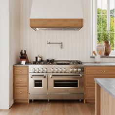 a stove top oven sitting inside of a kitchen next to wooden cabinets and counter tops