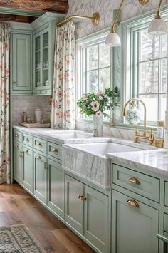 a kitchen with green cabinets, marble counter tops and gold faucet lighting over the sink