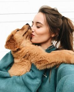 a woman holding a dog in her arms and kissing it's face on the nose