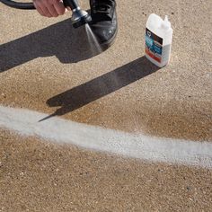 a person is spraying water onto the ground with a sprayer and a canister