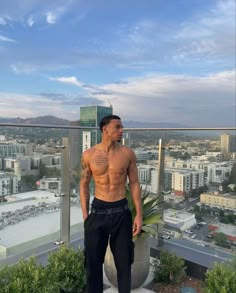 a shirtless man standing on top of a building next to a tall planter