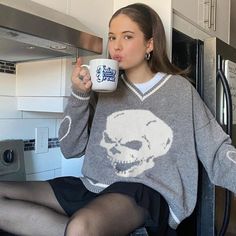 a woman sitting on the counter drinking from a mug