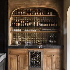 a wine cellar with lots of bottles and glasses on the shelves, along with an oven