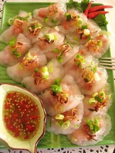 a green plate topped with sushi and sauce next to a bowl of dipping sauce