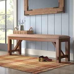 a wooden bench sitting on top of a rug in front of a window next to a wall