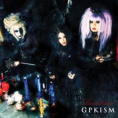 three women dressed in gothic clothing sitting next to each other on a table with candles