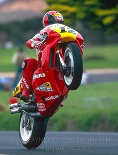 a man riding on the back of a red motorcycle