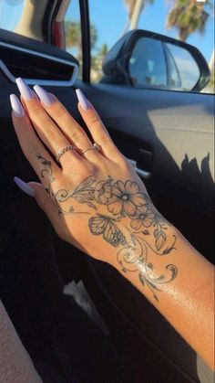 a woman's hand with flowers on her left wrist and tattoos on her right arm