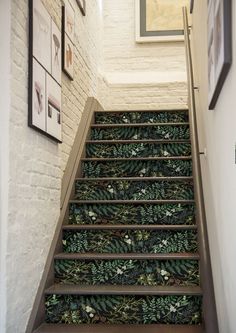 the stairs are decorated with green plants and pineconis on them, along with framed pictures