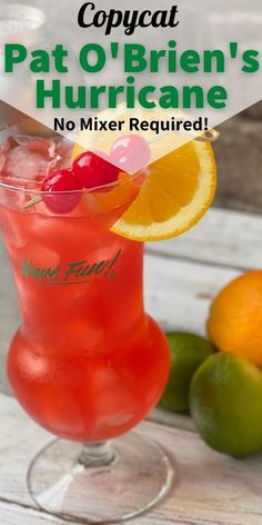 a close up of a drink in a glass on a table with fruit and limes