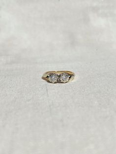 a three stone ring sitting on top of a white cloth covered surface with no one around it