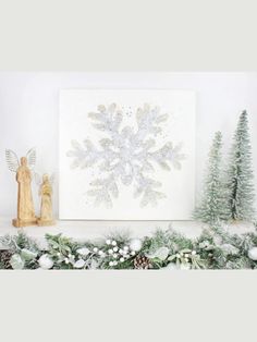 a christmas mantle with snowflakes, angel figurines and evergreens on it