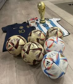 several soccer balls sitting on the floor next to a trophy