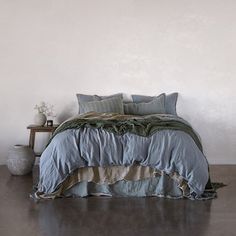 a bed with blue and green comforters in a room next to a table on the floor