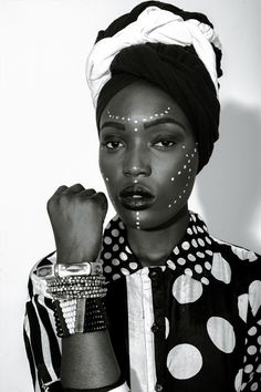 a woman with polka dots on her face and wearing a turban, holding a watch