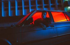 a man leaning out the window of a car at night