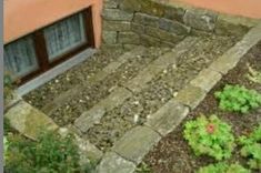 an outdoor area with stone steps and plants in the foreground, next to a pink building