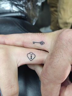 two people holding hands with tattoos on their fingers and one has a key to each other