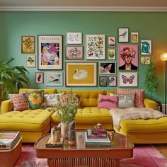 a living room filled with yellow couches and pictures on the wall above them,