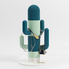 a cactus shaped sculpture with various items attached to the top and bottom of it, sitting on a white surface