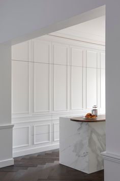 a kitchen with white cabinets and marble counter tops, along with an island in the middle