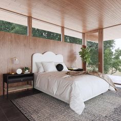 a large bed sitting in a bedroom next to a wooden wall with windows on each side