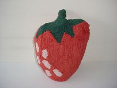 a red stuffed strawberry sitting on top of a white table