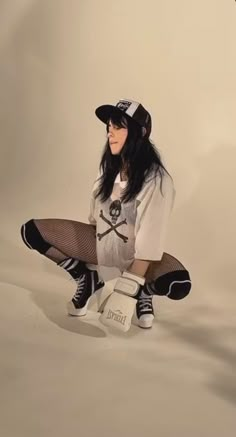 a young woman sitting on top of a skateboard wearing black and white clothing with her legs crossed