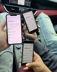 two people holding their cell phones while sitting in a car