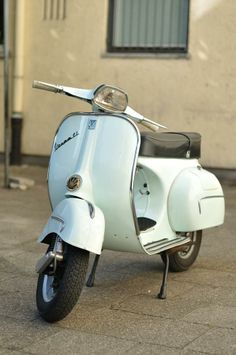 a white scooter is parked on the sidewalk