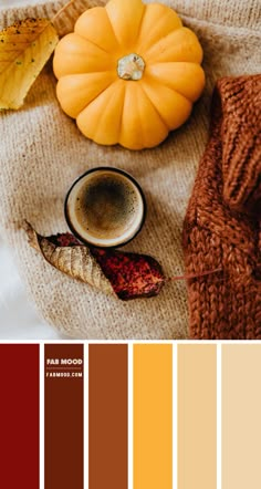 a cup of coffee next to some autumn leaves and a pumpkin on a white blanket