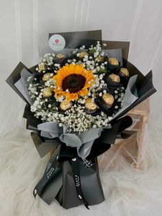 a bouquet of sunflowers and chocolates in black paper wrapped around the stems