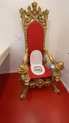 a white toilet sitting on top of a red floor next to a gold throne chair