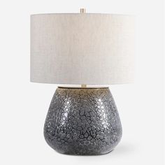 a table lamp with a white shade on it and a gray crackled ceramic base