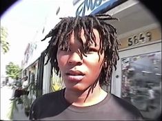 a close up of a person with dreadlocks in front of a storefront