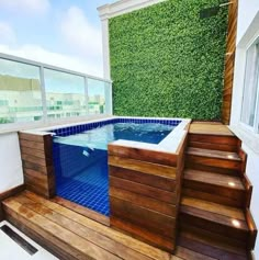 an outdoor hot tub with steps leading up to it and a green wall in the background