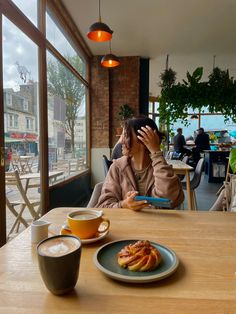 a woman sitting at a table in front of a plate of food and cup of coffee