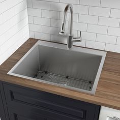 a stainless steel kitchen sink with wooden counter top