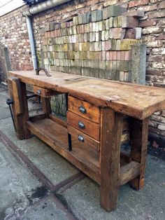 an old wooden table with two drawers on one side and a brick wall in the background