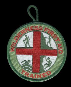 a patch with the words wilderness first and a cross on it in red, green and white