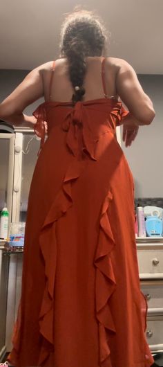 a woman in an orange dress looking at herself in the mirror