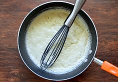 a pan filled with batter and whisk on top of a wooden table